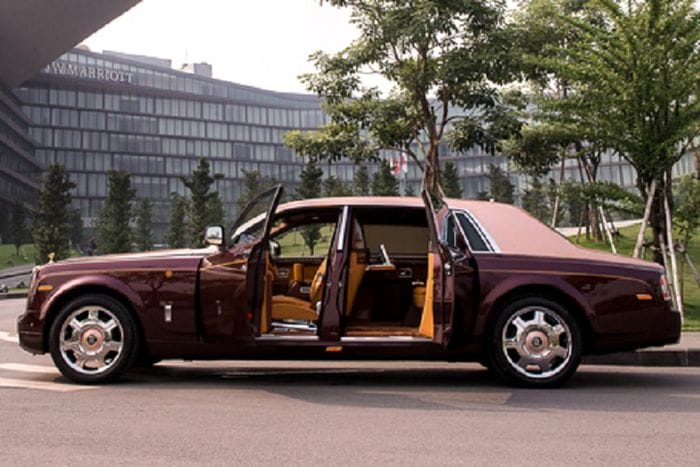 Điểm xuyết trên màu sơn đỏ Madeira của Rolls-Royce Phantom Lửa thiêng của Trịnh Văn Quyết còn có một số chi tiết sơn màu vàng hồng Sunrise thể hiện sự sung túc, ấm no. Chưa hết, xe còn có biểu tượng Spirit of Ecstasy mạ vàng.