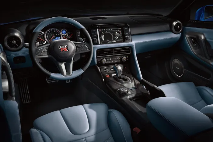  Nội thất của Nissan GT-R Skyline Edition mang tông màu xanh Sora Blue. Logo "Skyline Edition" được bố trí tại tựa tay trung tâm ốp sợi carbon. 